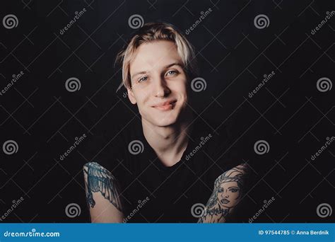 retrato de un individuo rubio joven con los tatuajes y las perforaciones en un fondo negro