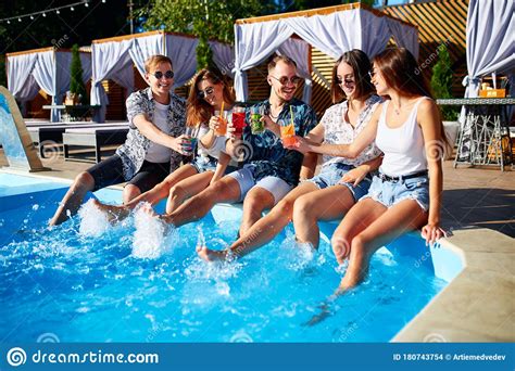 Group Of Friends Having Fun At Poolside Party Clinking Glasses With