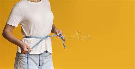 Unrecognizable Woman In White T Shirt Measuring Thin Waist With Tape