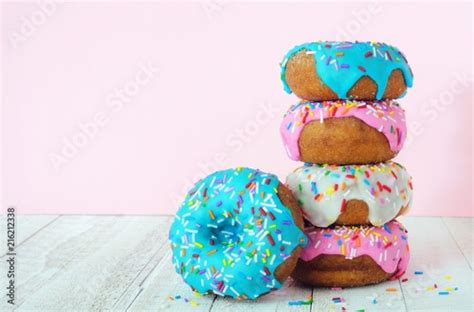 Stack Of Donuts With Pastel Colored Icing On A Soft Pink Background