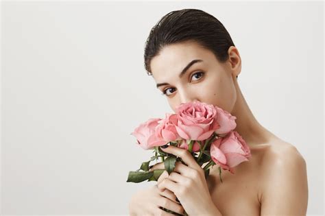 Free Photo Sensual Girlfriend Smelling Bouquet Of Roses While Standing Naked On Grey