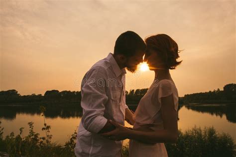 Couple Standing On A River Shore Kissing While Sun Is Setting Stock Photo Image Of Adult