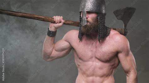 Muscular And Shirtless Warlike Viking With Helmet And Axe On His