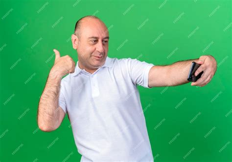 Free Photo Pleased Casual Mature Man Take A Selfie And Points At Side Isolated On Green Background