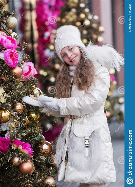 Portrait Of A Sweet Smiling Girl In A White Knitted Cap And White Coat