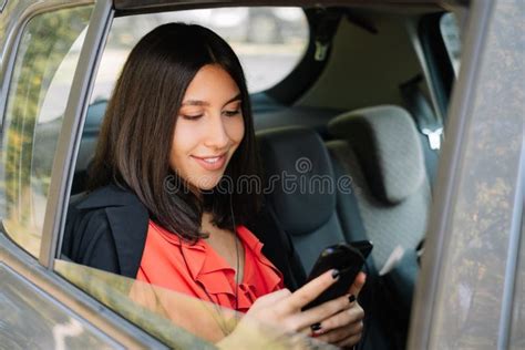 Elegant Girl Using Her Mobile While Sitting In Backseat Stock Image