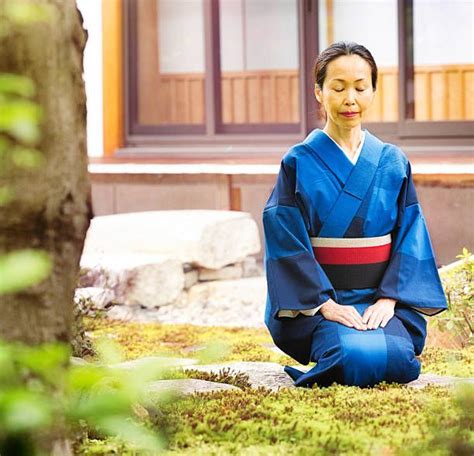 Mature Japanese Female Buddhist Meditating In Temple Garden Kneeling