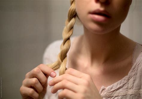 Blond Woman Twisting Hair Into A Braid Closeup By Stocksy Contributor