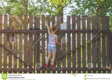 Girl Climbs The Fence On A Summer Day Stock Image Image Of Caucasian