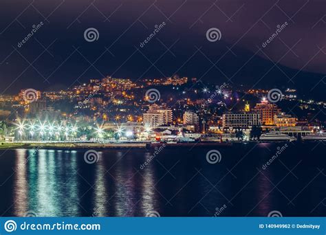 Yalta Embankment At Night City Buildings Lights Reflected In Black