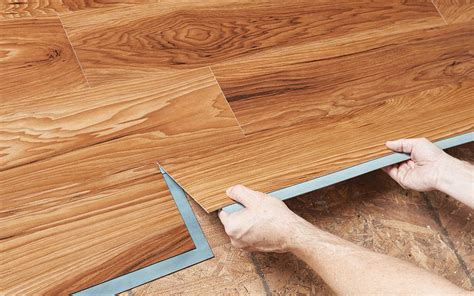 Two Hands Install A Grip Strip Vinyl Plank Over A Plywood Subfloor