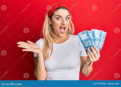 Young Caucasian Woman Holding 1000 Hungarian Forint Banknotes Celebrating Achievement With Happy