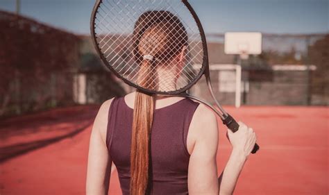 Красивая и стройная девушка с ракеткой играет в теннис девушка стоит спиной к зрителю Премиум