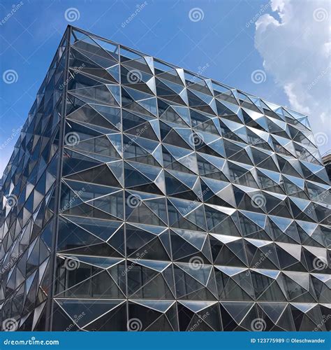 Modern Futuristic Office Building With Reflection Of Clouds And Blue