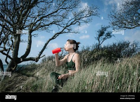 Fit Sporty Woman Sitting Taking A Drink Of Water After Exercise Outside