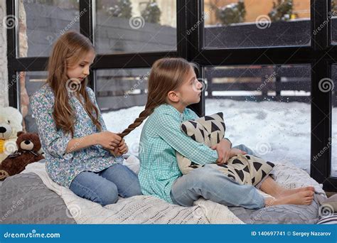 the image of two cute little sisters sitting on windowsill in peace and quiet stock image
