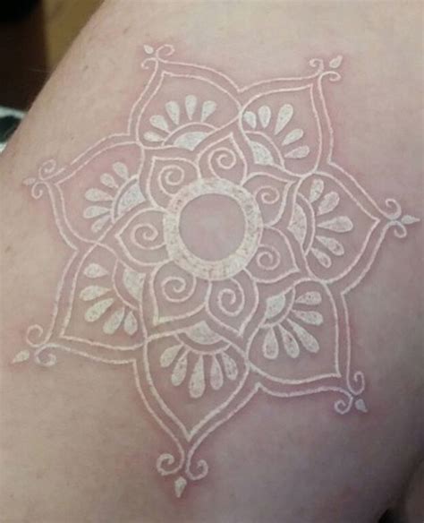 A White Tattoo On The Back Of A Womans Arm With An Intricate Design