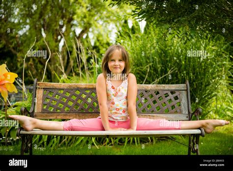 Child Little Girl Performing Gymnastic Pose On Bench Outdoor In