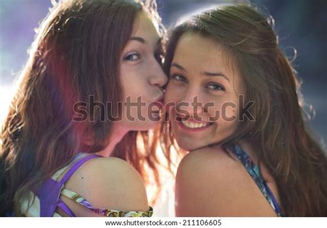 Girl Kissing His Girlfriend And Looking At The Camera