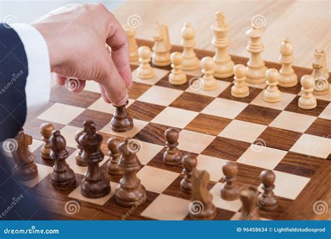 Businessman Holding Chess Figure While Playing Chess Alone Stock Photo