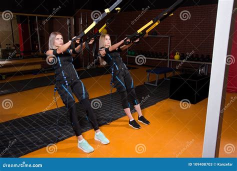 Two Beautiful Woman In Electrical Muscular Stimulation Suit Doing Squat