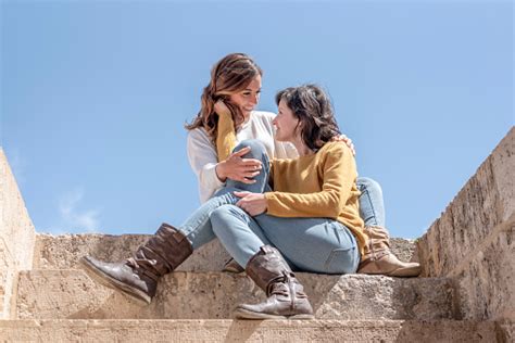 a lesbian couple embracing and looking each other in the eyes sitting on the stairs in the