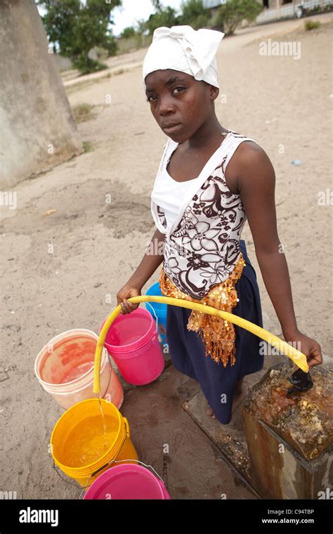A Young Woman Fills Buckets Of Water At A Community Well Outside Dar Es