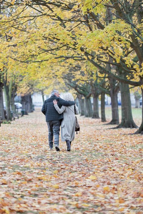 Affectionate Couple Hugging Walking Among Trees And Leaves In Autumn
