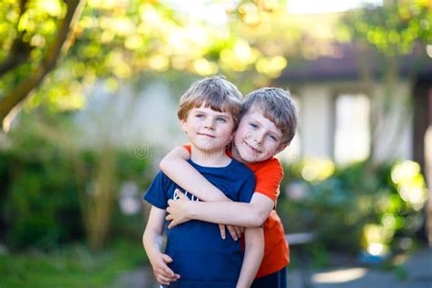 Two Little Active School Kids Boys Twins And Siblings Hugging On