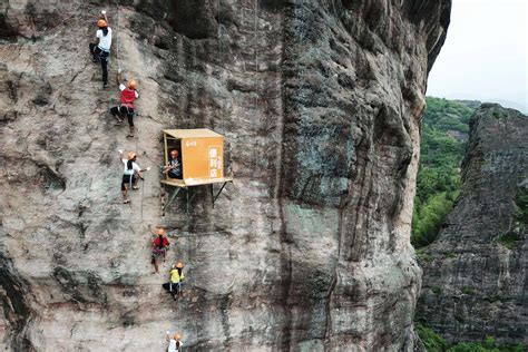 People Climb On A Cliff Face Past A 100 Meter High Convenience Store In