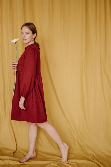 Woman In Red Long Sleeve Dress Standing Beside Yellow Curtain · Free
