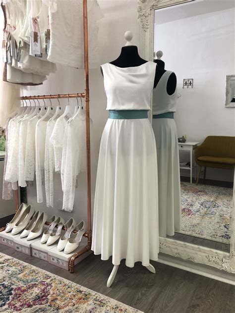 A White Dress On Display In Front Of A Mirror With Shoes Hanging From