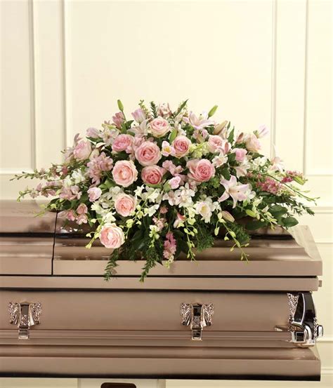 Ceramic white casket with a teddy bear on a background of pink flowers and hearts. An Elegant Tribute Casket Spray at From You Flowers