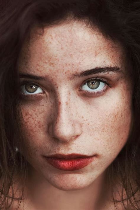 A Woman With Freckles On Her Face And Blue Eyes Is Looking At The Camera