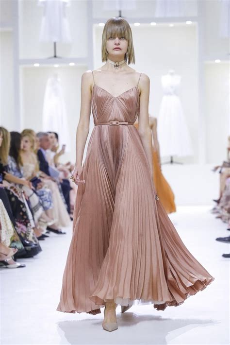 A Model Walks Down The Runway In A Pink Pleated Dress And High Heeled