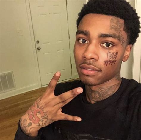 A Man With Tattoos On His Face Making The Peace Sign