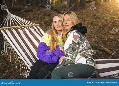 Two Cute Blonde Women Sitting In The Hammock And Laughing In The Sunny Forest Stock Image