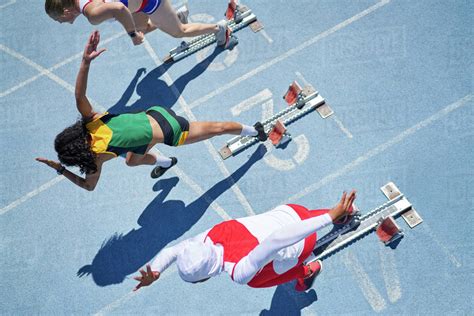 Female Track And Field Athletes Taking Off From Starting Blocks Stock