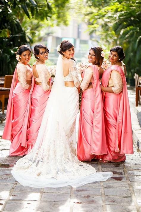 A Group Of Women Standing Next To Each Other In Pink Sari Dresses And