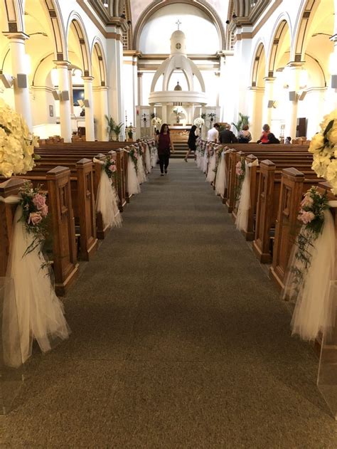 The Aisle Is Decorated With White Flowers And Tulle Skirted Pews For An