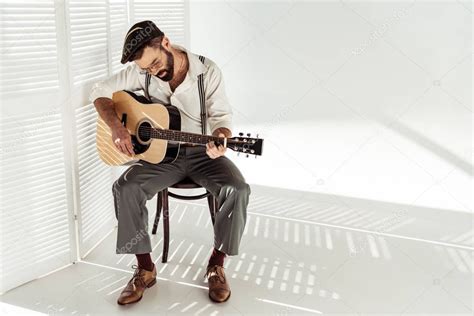 Handsome Bearded Man Cap Sitting Chair Playing Guitar White Room Stock