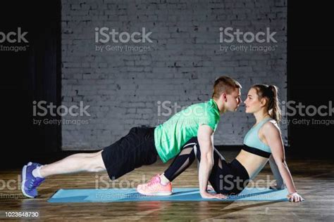 Shot Of A Cute Couple Kissing Each Other While Doing Exercise In Gym