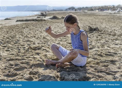 La Ragazza Sta Sedendosi Sulla Spiaggia Fotografia Stock Immagine Di Litorale Capelli