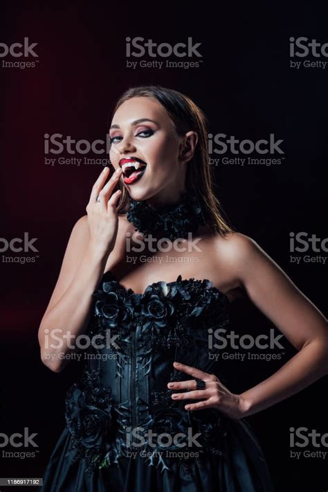 Scary Vampire Girl With Fangs In Black Gothic Dress Isolated On Black