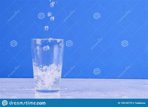 Agua Que Salpica Del Vidrio Aislado En Un Fondo Azul Imagen De Archivo