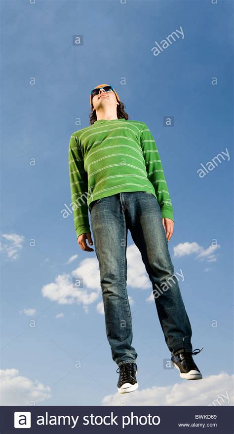 Portrait Of Casually Dressed Man In High Jump Against Bright Blue Sky