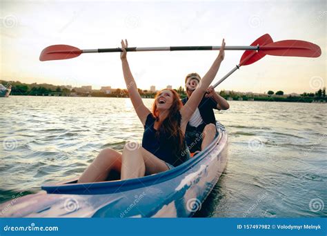 Confident Young Couple Kayaking On River Together With Sunset On The