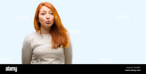 Beautiful Young Redhead Woman Expressing Love Blows Kiss At Camera Flirting Isolated Over Blue