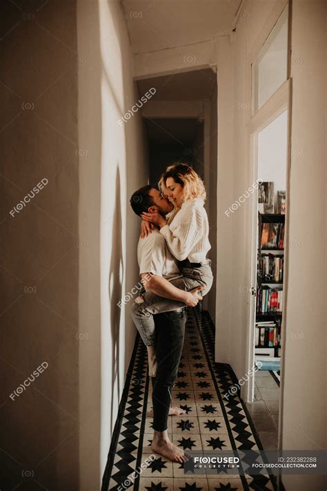 Passionate Man And Woman Embracing And Kissing At Wall In Hall At Home
