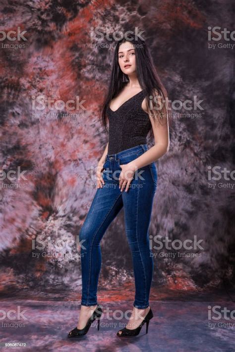beautiful curvy woman posing in black shirt and jeans on multicolored background plus size model